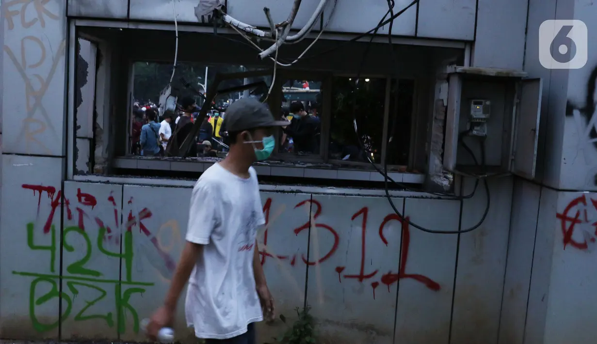 Seorang anak muda melintasi Pos Polisi yang dirusak massa di kawasan Gondangdia, Jakarta, Kamis (8/10/2020). Aksi anarkis massa dilakukan saat berunjuk rasa menentang disahkan Omnibus Law UU Cipta Kerja. (Liputan6.com/Helmi Fithriansyah)