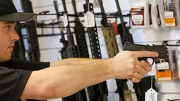 Penjaga toko senjata, Ryan Martinez saat memegang senjata di Utah, AS, (21/6). Senat Amerika Serikat  menolak empat Rancangan Undang-Undang Pengendalian Senjata Api yang dibuat sebagai respons dari penembakan massal di Orlando. (REUTERS / George Frey)