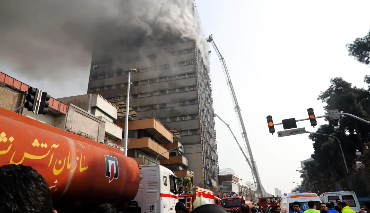 Petugas pemadam kebakaran berusaha menjinakkan api yang melahap gedung pencakar langit tertua Iran, gedung Plasco, di pusat kota Teheran, Kamis (19/1). Bangunan berlantai 15 itu runtuh menyusul kebakaran hebat yang terjadi. (AFP PHOTO/STR)