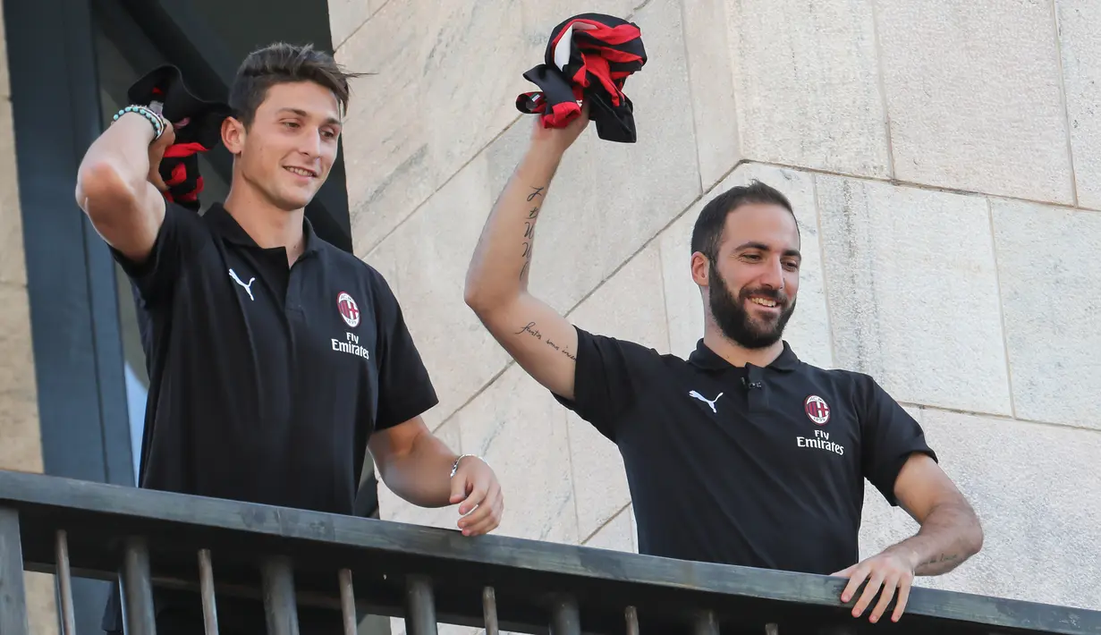 Pemain baru AC Milan, Gonzalo Higuain dan Mattia Caldara melempar jersey ke suporter dari balkon di alun-alun pusat Milan Piazza Duomo (3/8). Caldara didapatkan secara permanen dan menandatangani kontrak sampai 30 Juni 2023. (AFP Photo/Stringer)