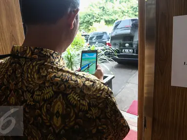 Seorang pria bermain game virtual Pokemon Go di samping kertas larangan, di lingkungan Istana Negara, Jakarta, Rabu (20/7). Pihak Istana Kepresidenan mulai menerbitkan larangan bermain Pokemon Go di area Istana. (Liputan6.com/Faizal Fanani)