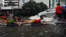 Sejumlah bocah asyik bermain di pembatas jalan saat banjir melanda kawasan Sarinah, Jakarta, Senin (9/2/2015). (Liputan6.com/Johan Tallo)