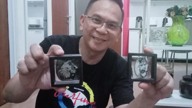 Muchlis menunjukkan batu koleksinya yang bergambar kepala orang dan satunya lagi kepala burung. (Foto: Bam Sinulingga/Liputan6.com)