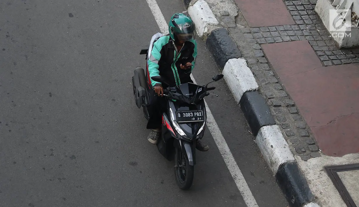 Pengendara sepeda motor mengoperasikan gawainya saat berkendara di Jakarta, Jumat (8/2). Menggunakan GPS saat berkendara dianggap melanggar UU Nomor 22 Tahun 2009 tentang Lalu Lintas dan Angkutan Jalan. (Liputan6.com/Immanuel Antonius)