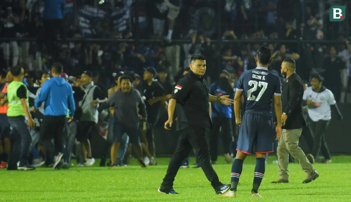 Pemain, ofisial, dan perangkat pertandingan laga Arema Vs Persebaya diberikan kawalan ketat untuk masuk ke dalam ruang stadion karena mereka tak henti-hentinya dilempari botol dan benda-benda lainnya dari tribun Stadion Kanjuruhan, Malang, pada Sabtu (1/10/2022) malam. (Bola.com/Iwan Setiawan)