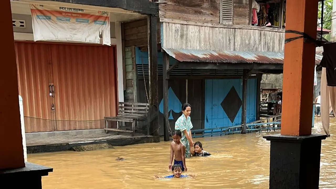 Seorang perempuan menemani anak-anak bermain di tengah bencana banjir.