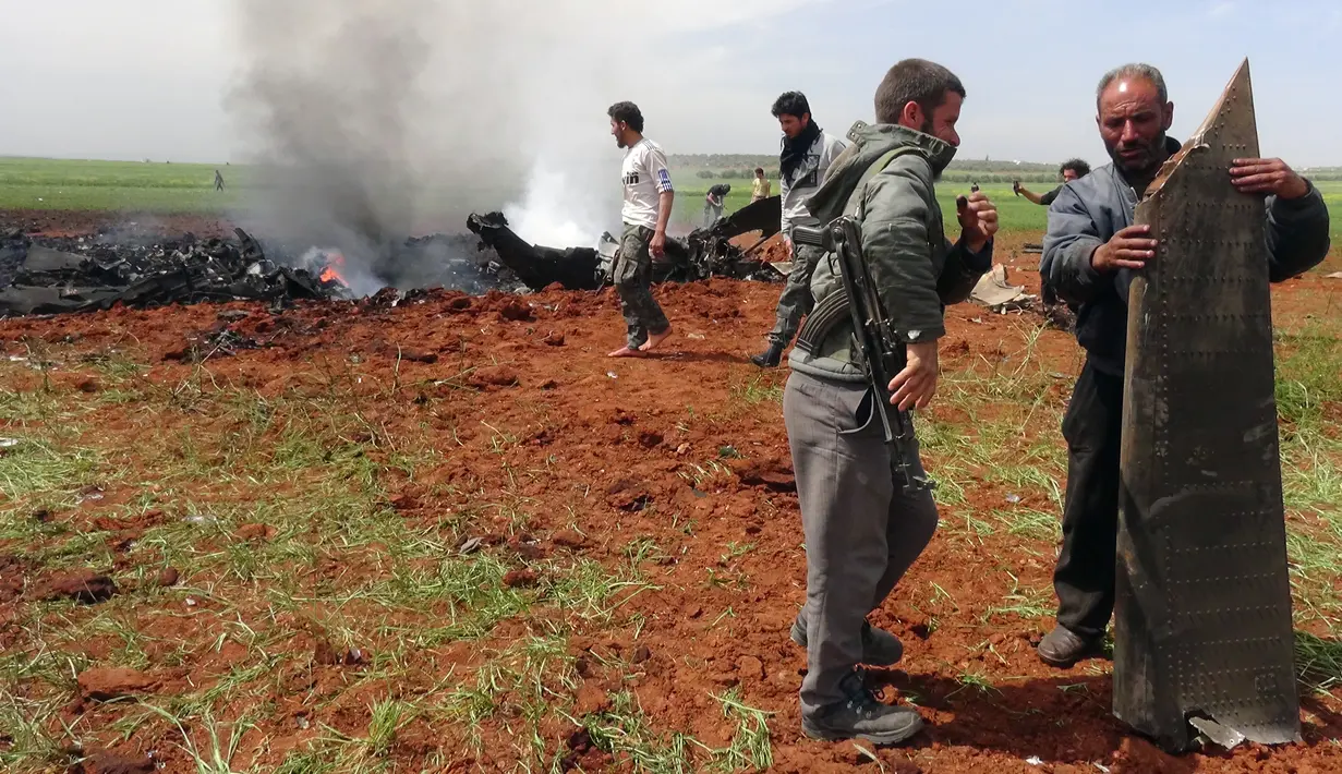 Petugas memeriksa pesawat Su-22 milik Angkatan Udara Suriah yang ditembak jatuh di wilayah selatan Aleppo, Selasa (5/4). Sayap kelompok teroris Al-Qaeda di Suriah, Front al-Nusra, menembak jatuh jet SU-22 tersebut menggunakan roket. (OMAR HAJ KADOUR/AFP)