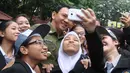 Sejumlah siswa SMKN 27 Jakarta ber-selfie bersama Gubernur DKI Basuki 'Ahok' Tjahaja Purnama sebelum memulai Ujian Nasional (UN), Senin (13/4/2015). (Liputan6.com/Herman Zakharia)