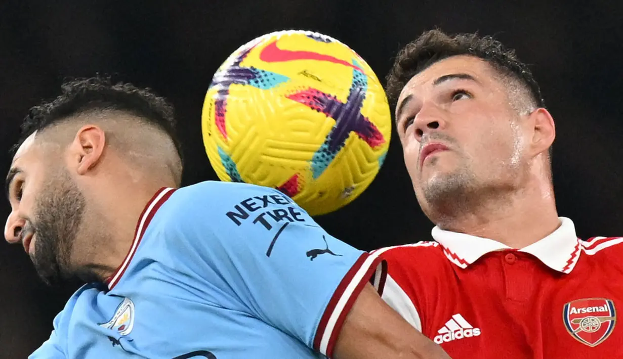 Pemain Arsenal, Granit Xhaka (kanan) berebut bola dengan pemain Manchester City, Riyad Mahrez pada laga pekan ke-23 Liga Inggris 2022/2023 yang berlangsung di Emirates Stadium, London, Kamis (16/02/2023) WIB. (AFP/Glyn Kirk)
