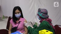 Petugas kesehatan menyuntikkan vaksin COVID-19 di sentra vaksin Tomang Tol Plaza, Tangerang, Sabtu (24/7/2021). Target pemerintah dalam pelaksanaan vaksinasi Covid-19 bertambah menjadi 208,2 juta orang yang sebelumnya sebanyak 181,5 juta atau 70 persen dari total populasi. (Liputan6.com/Angga Yuniar