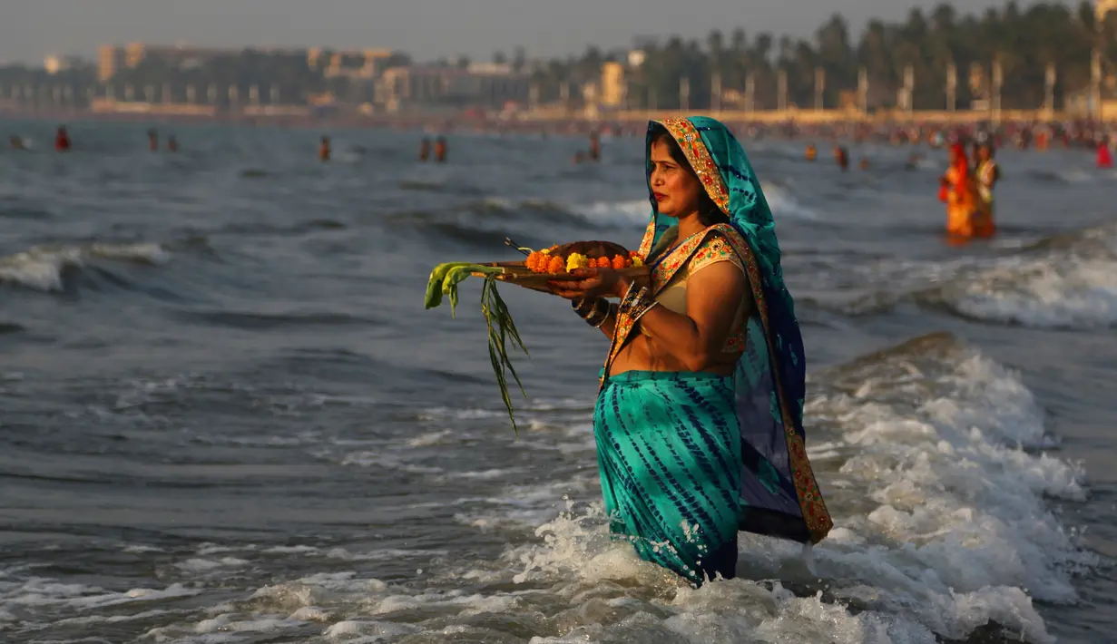 Umat Hindu India berdoa sambil berdiri di perairan Laut Arab saat matahari terbenam selama Festival Chhath di Mumbai, Selasa (13/11). Festival Hindu kuno ini bentuk terima kasih kepada Dewa Matahari yang menopang kehidupan di bumi. (AP/Rafiq Maqbool)