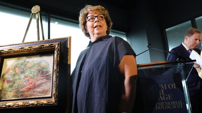 Cucu pewaris terakhir, Sylvie Sulitzer berpose dengan lukiskan karya Renoir yang dikembalikan dalam upacara di New York, Rabu (12/9). Lukiskan itu dikembalikan setelah 70 tahun berkelana dari Afrika Selatan, London, Swiss dan New York. (SPENCER PLATT/AFP)