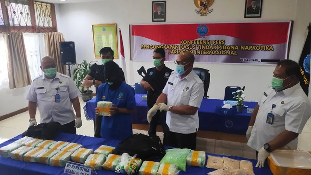 Kurir sabu dari sindikat narkoba internasional memegang barang bukti narkoba yang disita Badan Narkotika Nasional Provinsi Riau.