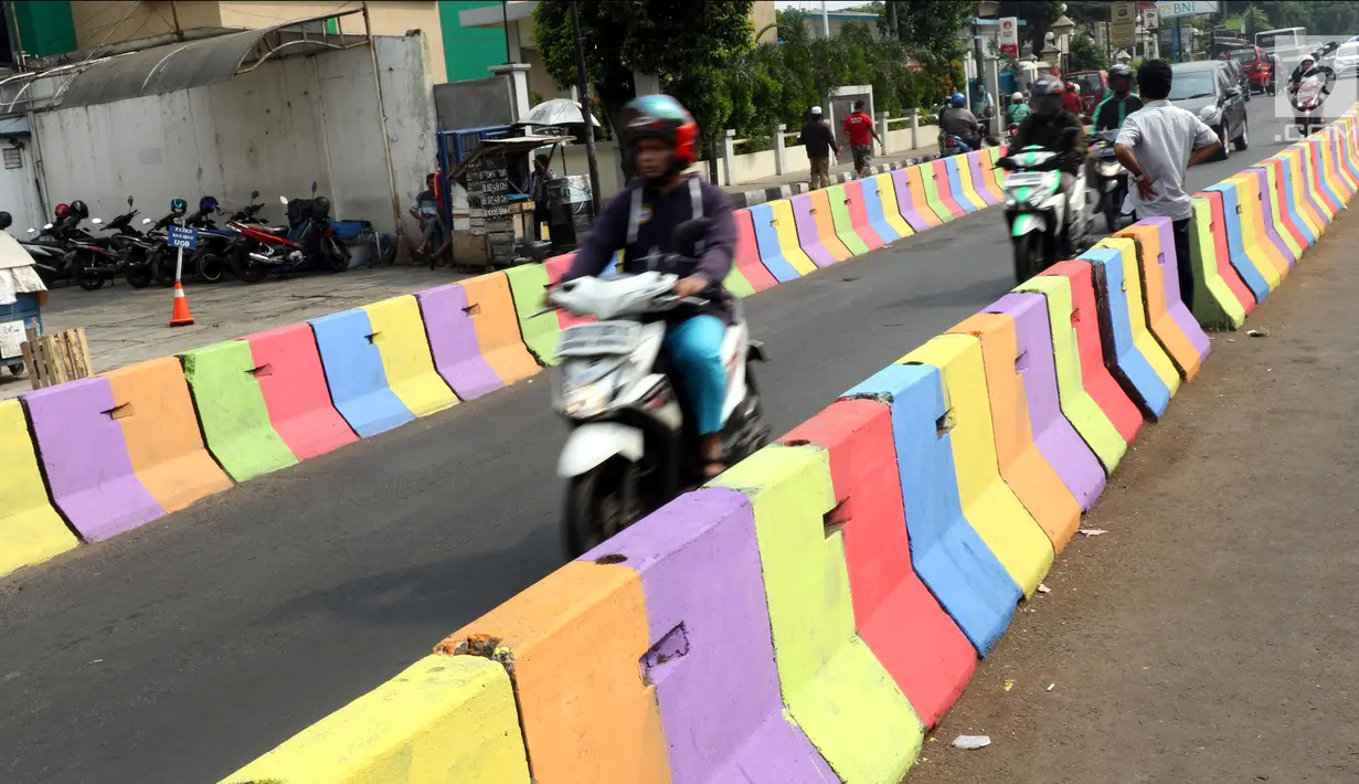 Pengendara motor melintasi di sisi pemisah jalan di Jalan Raya Ragunan sekitar Pasar Minggu, Jakarta, Selasa (24/7). Di kawasan ini pemisah jalan di cat warna warni sehingga terlihat lebih semarak. (Liputan6.com/Helmi Fithriansyah)