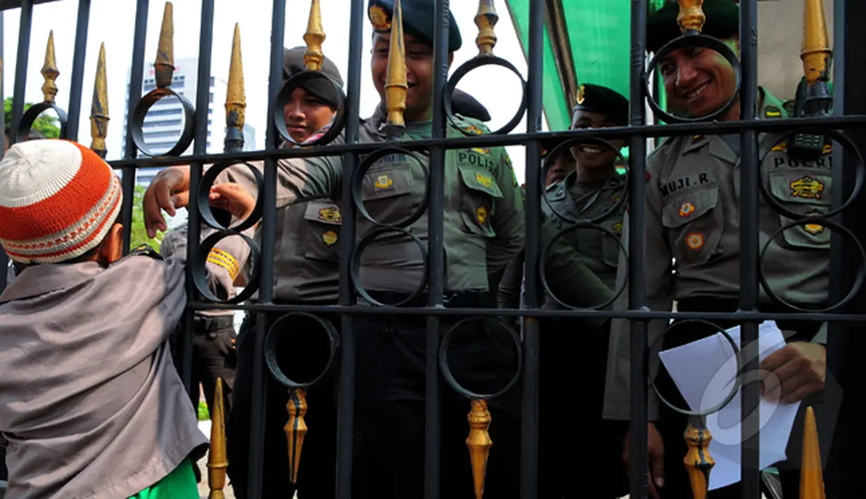 Seorang bocah mencoba bersalaman dengan Polisi yang berjaga di sekitar Balaikota saat aksi massa yang menilai Gubernur Ahok gagal menjalankan pemerintahan dalam 100 hari (Liputan6.com/Faisal R Syam)