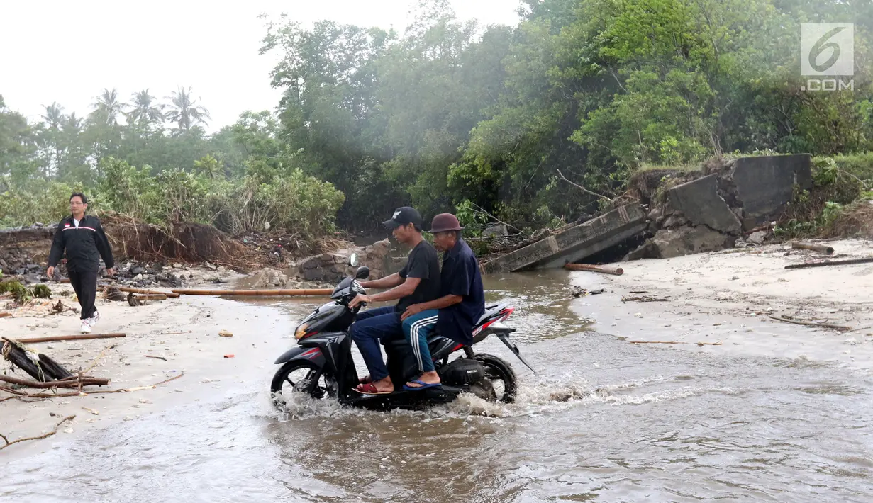 Kendaraan bermotor melintasi pantai karena jembatan di jalur alternatif Sumur, Banten, ambruk, Senin (24/12). Jembatan penghubung ambruk diterjang gelombang Tsunami Selat Sunda. (Liputan6.com/Angga Yuniar)