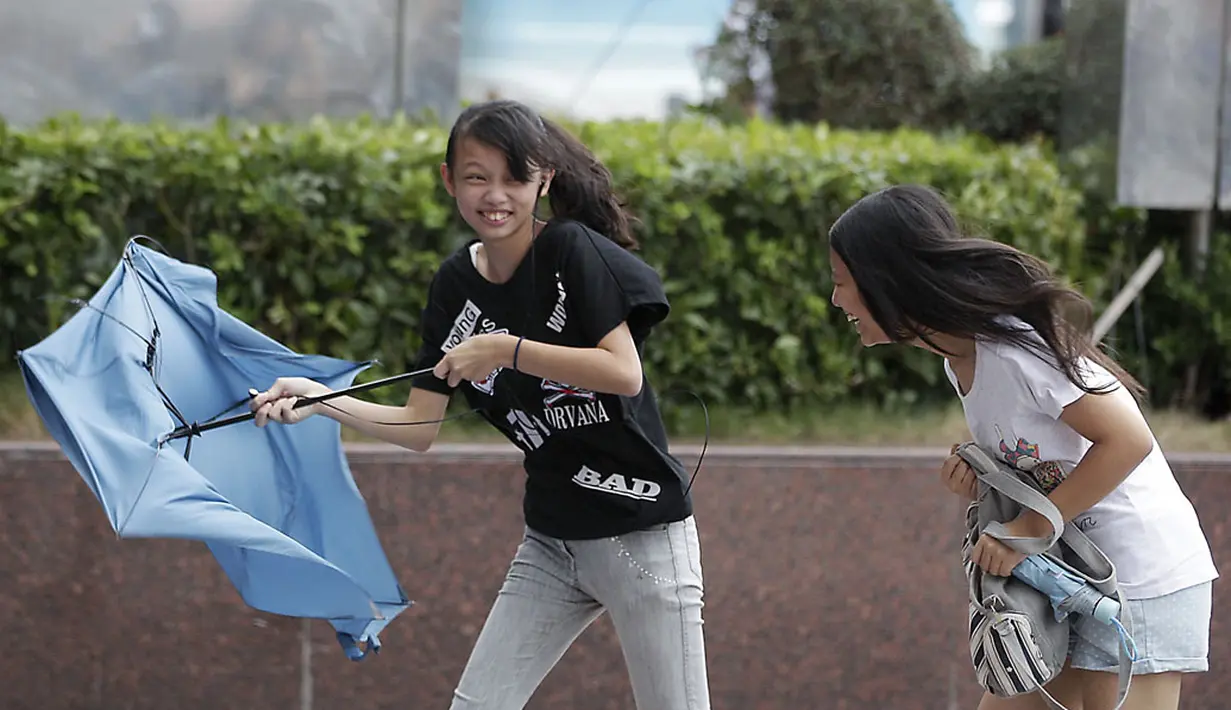 Beberapa gadis memegangi payung mereka saat badai tropis Fung-Wong memasuki wilayah Taiwan, (21/9/2014). (REUTERS/Pichi Chuang)