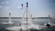Seorang flyboarder (tengah) memberi hormat saat gladi bersih sehari jelang upacara pembukaan latihan angkatan laut multilateral Komodo 2025 di pelabuhan Benoa, Denpasar, Bali, pada 15 Februari 2025. (SONNY TUMBELAKA/AFP)