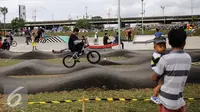 Seorang ayah yang menggendong anak menonton aksi pesepeda BMX Taman Kalijodo, Jakarta, Minggu (15/01). Sejak skate park dan lintasan sepeda BMX dibuka untuk umum, taman tersebut tidak pernah sepi pengunjung. (Liputan6.com/Fery Pradolo)