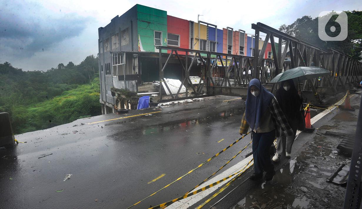 Warga melintasi ruas jalan Jembatan Cikreteg yang longsor di akses jalan nasional Bogor-Sukabumi, Caringin, Kabupaten Bogor, Jawa Barat, Kamis (2/3/2023). Jembatan rangka baja ini dipasang untuk penanganan darurat dan nanti hanya bisa dilalui kendaraan roda empat dan roda dua saja. (merdeka.com/Arie Basuki)
