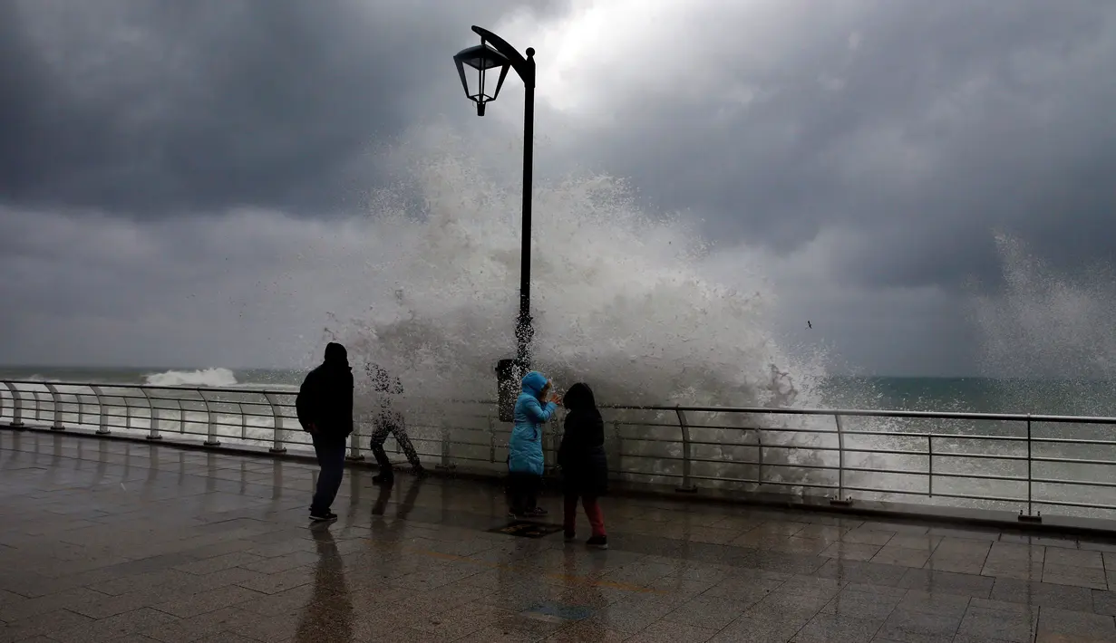 Warga berada di dekat ombak besar di Beirut, Lebanon (6/1). Badai kuat di Lebanon membawa suhu dingin dan salju ke pegunungan dan hujan lebat, angin kencang melanda pantai bagian dari negara Mediterania tersebut. (AP Photo/Bilal Hussein)