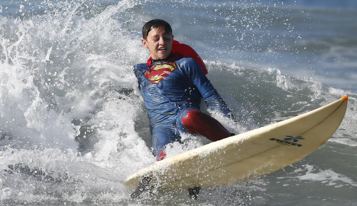 Peserta berselancar dengan mengenakan pakaian Superman selama ikuti lomba selancar di Santa Monica, Amerika Serikat, Sabtu (31/10/2015). Perlombaan ini mewajibkan peserta mengenakan kostum bertema Halloween. (REUTERS/Lucy Nicholson)