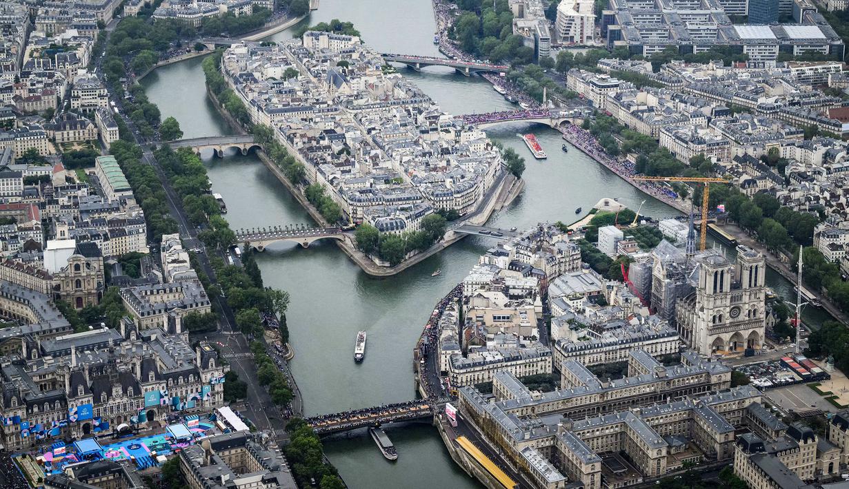 Foto udara saat perahu delegasi saat berlayar di Sungai Seine melewati Pulau Ile de la Cite (depan) dan Pulau Saint-Louis (belakang) selama upacara pembukaan Olimpiade Paris 2024, Paris, Prancis, 26 Juli 2024. (AFP/Pool/Lionel Bonaventure)