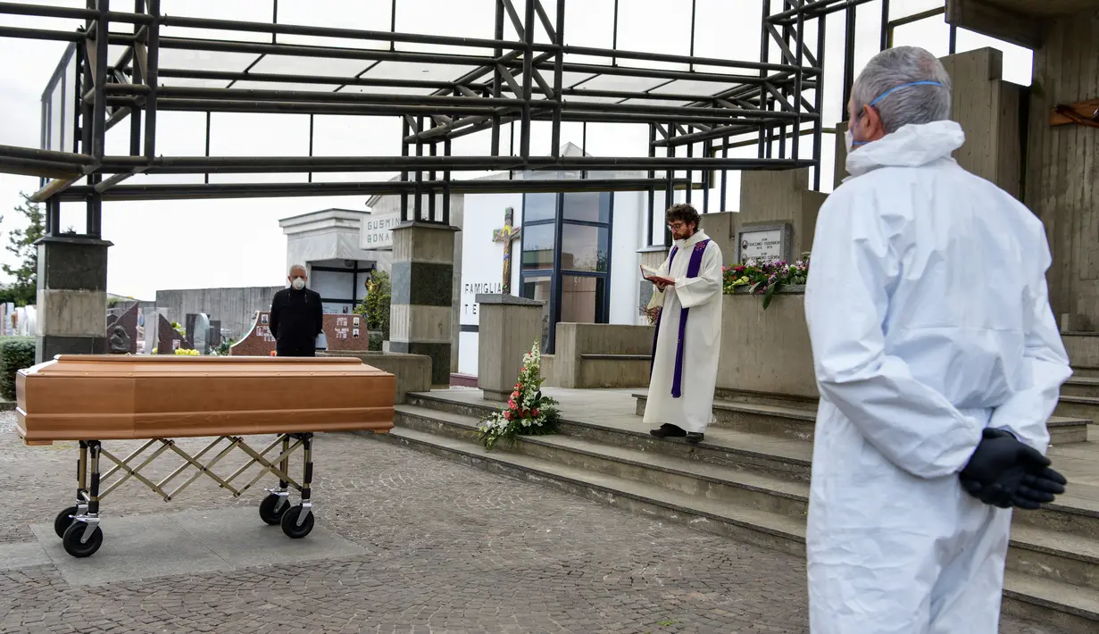 Seorang Pastor membaca doa pada upacara pemakaman warga yang meninggal saat upacara pemakaman tanpa kehadiran dari sanak saudaranya yang sedang menghadapi karantina selama masa lockdown di pemakaman Grassobbio, Lombardy, Italia, Senin (23/3/2020). (Piero CRUCIATTI / AFP)