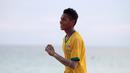 Seorang pemuda menggunakan jersey Brasil saat bermain bola dekat pantai di Desa Matwaer, Kei Kecil, Maluku (25/12/2017). Bermain bola di pasir menjadi daya tarik tersendiri bagi anak-anak dan pemuda desa. (Bola.com/Nick Hanoatubun)