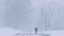 Seorang pria berjalan di bawah salju lebat saat terjadi badai salju di Manville, New Jersey (21/3). Salju tebal yang menutup jalanan ini berpotensi membahayakan warganya. (AP/Julio Cortez)