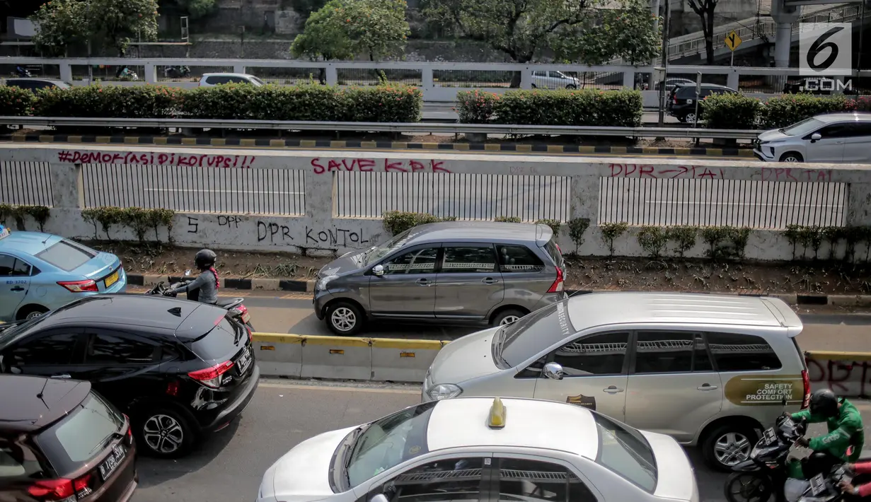 Pengendara melintasi dekat coret-coretan (vandalisme) di sekitar Gedung DPR/MPR RI, Jakarta, Selasa (24/9/2019). Demonstrasi mahasiswa dari berbagai kampus yang menolak pengesahan RUU Kitab Undang-Undang Hukum Pidana(KUHP) tercoreng oleh aksi vandalisme. (Liputan6.com/Faizal Fanani)