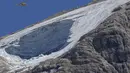 <p>Helikopter penyelamat terbang di atas gletser Punta Rocca yang runtuh dekat Canazei di Pegunungan Alpen Italia di Italia utara (4/7/2022). Tim penyelamat mengatakan kondisi lereng bawah dari gletser, yang telah mencair selama beberapa dekade, masih terlalu tidak stabil. (AP Photo/Luca Bruno)</p>