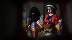 Anggota keluarga Palestina al-Yaqoubi berkumpul di sekitar meja membuat lentera bulan suci Ramadan untuk dijual selama penerapan lockdown di Khan Yunis, di Jalur Gaza selatan pada 15 April 2020. Karena pandemi Covid-19, keadaan berubah dan tradisi Ramadan pun tidak akan ada. (SAID KHATIB / AFP)