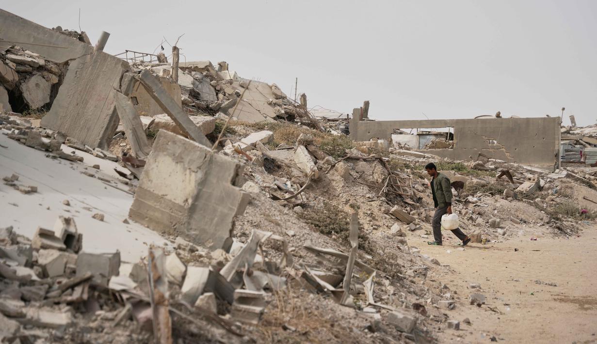 Seorang pria Palestina membawa wadah air di Kota Gaza, Selasa 12 Mei 2026. Kerusakan luas infrastruktur akibat serangan Israel sejak Oktober 2023 silam ditambah merosotnya ketersediaan air layak pakai, mendorong lebih dari dua juta warga Gaza ke ambang krisis keamanan air paling berbahaya. (AP Photo/Abdel Kareem Hana)