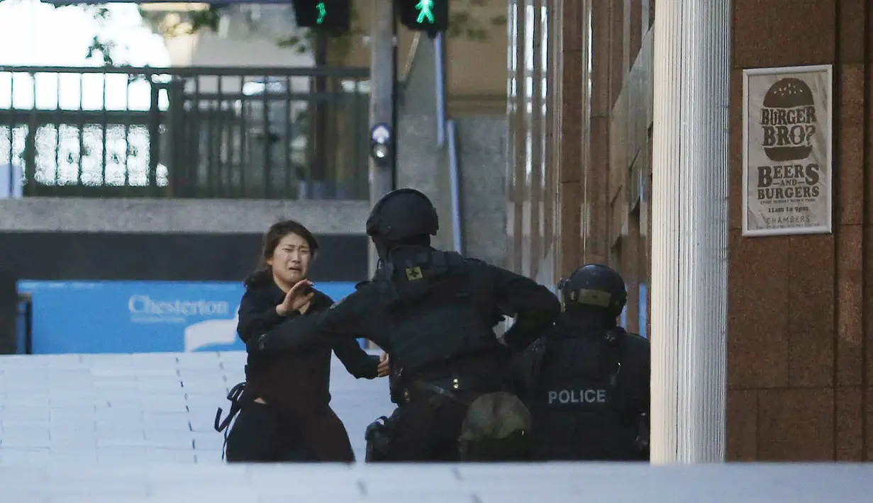 Seorang sandera langsung diamankan petugas kepolisian setelah berhasil keluar dari Kafe Lindt, Martin Place, Sydney, Senin (15/12/2014). (REUTERS/Jason Reed)