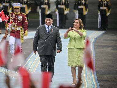 Presiden Republik Indonesia Prabowo Subianto (kiri) bersam Presiden Peru Dina Boluarte menyaksikan anak-anak mengibarkan bendera kedua negara sebelum pertemuan mereka di Istana Merdeka, Jakarta, pada 11 Agustus 2025. (Bay ISMOYO/AFP)