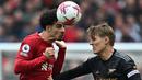 Gelandang Liverpool, Curtis Jones (kiri) memenangi duel udara dengan gelandang Arsenal, Martin Odegaard pada laga lanjutan pekan ke-30 Liga Inggris 2022/2023 di Anfield Stadium, Liverpool, Minggu (9/4/2023) malam WIB. (AFP/Paul Ellis)