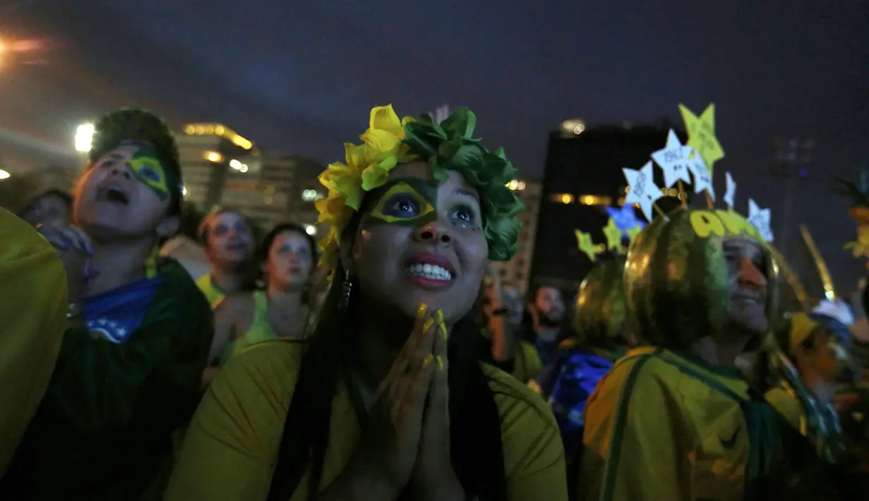 Ekspresi salah satu suporter Brasil menyaksikan tim asuhan Luiz Felipe Scolari berlaga melawan Kamerun melalui layar lebar di pantai Copacabana, Rio de Janeiro, (23/6/2014). (REUTERS/Pilar Olivares)