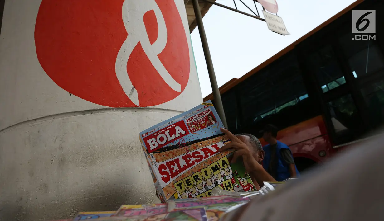 Pedagang membaca tabloid Bola di Terminal Kampung Melayu, Jakarta, Jumat (26/10). Hari ini menjadi terakhir tabloid Bola terbit. Tabloid Bola sudah menemani pencinta olahraga Tanah Air selama 34 tahun. (Merdeka.com/Imam Buhori)