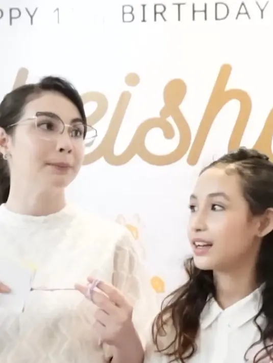 Sementara itu, Arumi mengenakan atasan putih bermotif dipadukan celana denim senada dengan putrinya yang sedang berulang tahun. Ia juga mengenakan kacamata clear dengan rambut ikat belakang bergaya ponytail. Wajahnya dipulas riasan natural. [@arumibachsin_94]