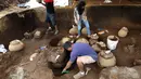 Pekerja Nicaraguan Institute of Culture (INC) menggali puluhan tembikar yang ditemukan di situs pemakaman zaman pra-Kolombia berusia lebih dari 1.200 tahun di lokasi pembangunan Stadion Bisbol Nasional yang baru di Managua, Selasa (20/6). (INTI OCON/AFP)
