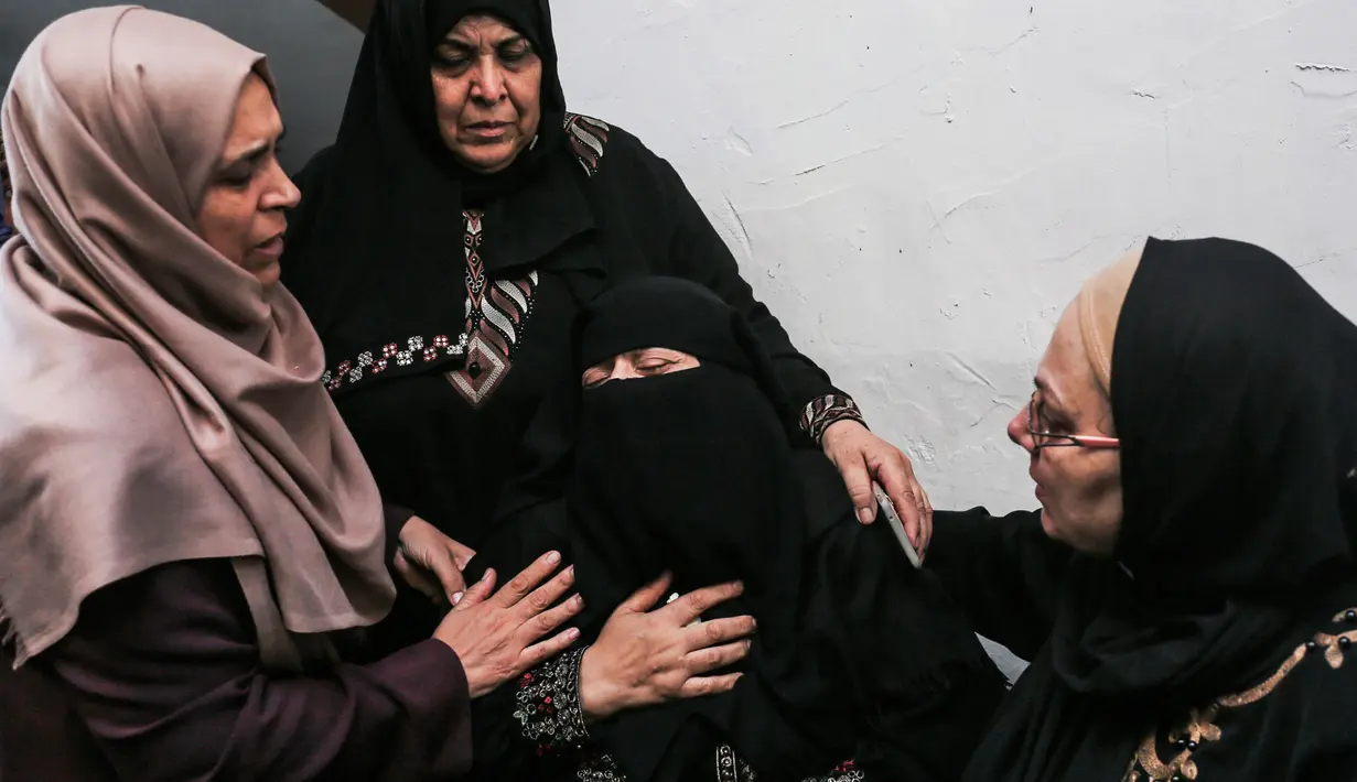 Kerabat korban paramedis Palestina, Abdullah al-Qutati yang meninggal ditembak tentara Israel menghibur ibu korban selama pemakaman putranya di Rafah, Jalur Gaza, Sabtu (11/8). (SAID KHATIB/AFP)