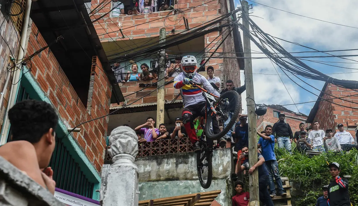 Warga menyaksikan aksi seorang pengendara sepeda saat mengikuti balapan Urban Bike Inder Medellin di gubuk comuna 1 di Medellin, Antioquia department, Kolombia (19/11). (AFP Photo/Joaquin Sarmiento)