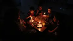 Sebuah keluarga Palestina menikmati makan sahur selama pemadaman listrik di kamp pengungsian Rafah, Jalur Gaza selatan, 11 Juni 2017. Israel mengumumkan pihaknya mengurangi pasokan listriknya ke Gaza atas permintaan Otoritas Palestina. (SAID KHATIB/AFP)