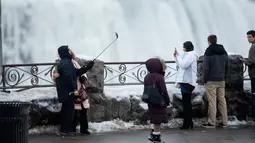 Sejumlah turis mengambil foto di depan Air Terjun Niagara, Ontario, Kanada, Senin (9/1). Air terjun Niagara adalah salah satu tempat wisata andalan Amerika Utara. (Geoff Robins/AFP)