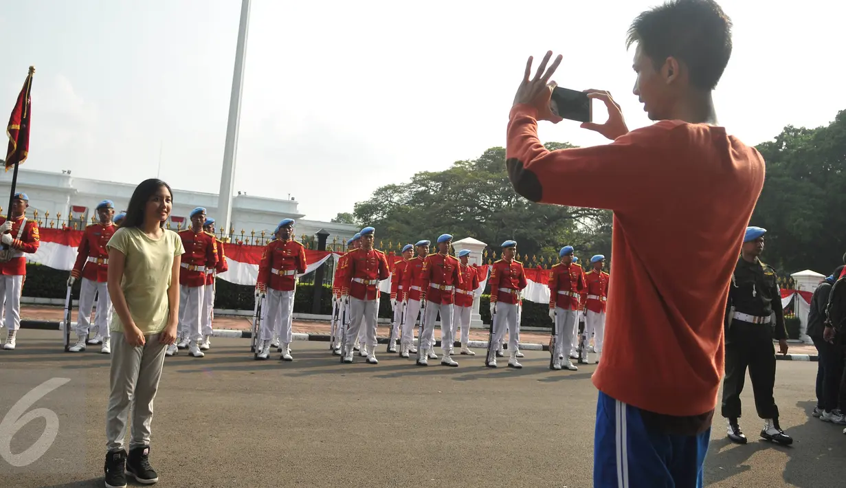 Warga berfoto di depan salah satu Pasukan Pengaman Presiden di depan Istana Negara, Miggu (17/7). Prosesi pergantian pasukan penjaga Istana Negara ini akan dijadikan objek atraksi wisata baru bagi masyarakat. (Liputan6.com/Gempur M Surya)