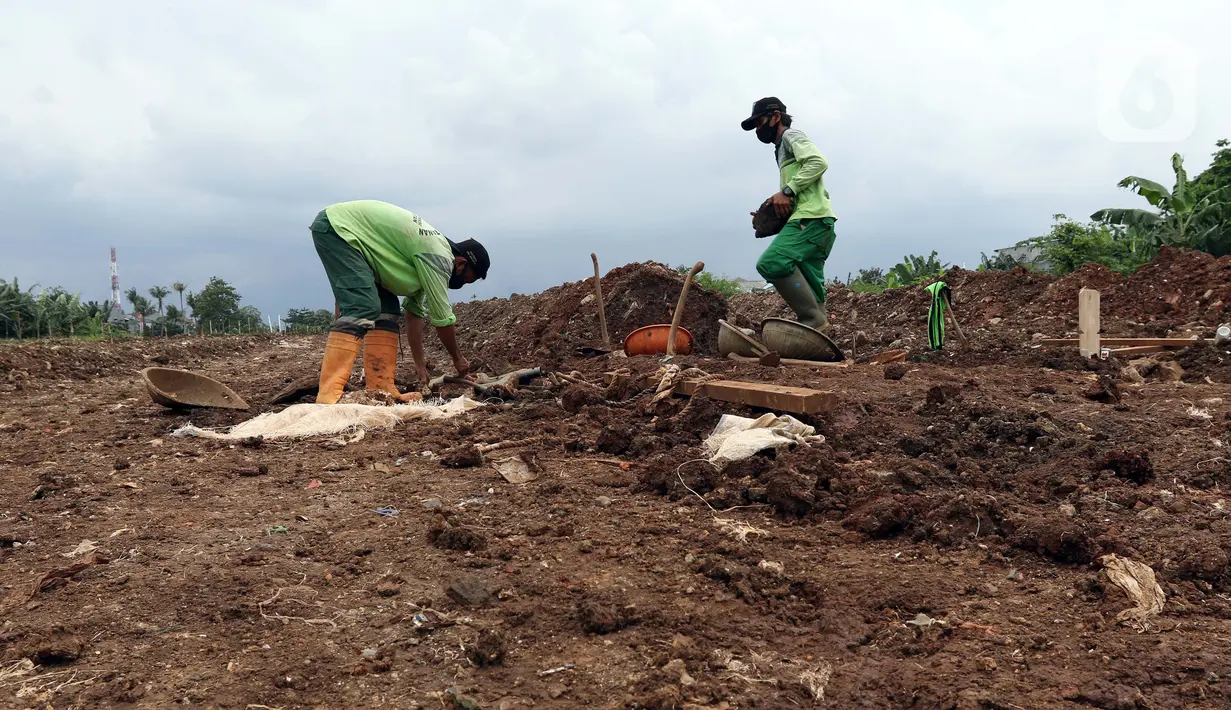 Petugas membuat jalur masuk kendaraan ke area khusus pemakaman jenazah dengan protokol COVID-19 di TPU Srengseng Sawah Dua, Jakarta, Selasa, (2/2/2021). TPU Srengseng Sawah 2, saat ini mulai menerima pemakaman jenazah protokol COVID-19 dengan kapasitas 1.020 petak. (Liputan6.com/Helmi Fithriansyah)