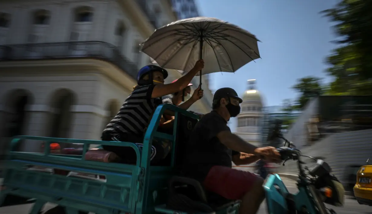 <p>Orang-orang mengendarai sepeda motor di depan Capitol di Havana, Kuba, Selasa (17/5/2022). Pemerintahan Presiden AS, Joe Biden mengumumkan akan melonggarkan pembatasan atas pengetatan yang diberlakukan selama pemerintahan Presiden Donald Trump terhadap Kuba dan mencabut batas saat ini $1.000 per kuartal yang dapat dikirim imigran kepada anggota keluarga yang masih tinggal di pulau itu. (AP Photo/Ramon Espinosa)</p>