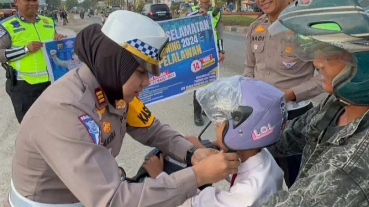 Kasat Lantas Polres Pelalawan AKP Akira Ceria memberikan helm kepada anak-anak dalam rangka Operasi Keselamatan Lancang Kuning jelang Ramadan.