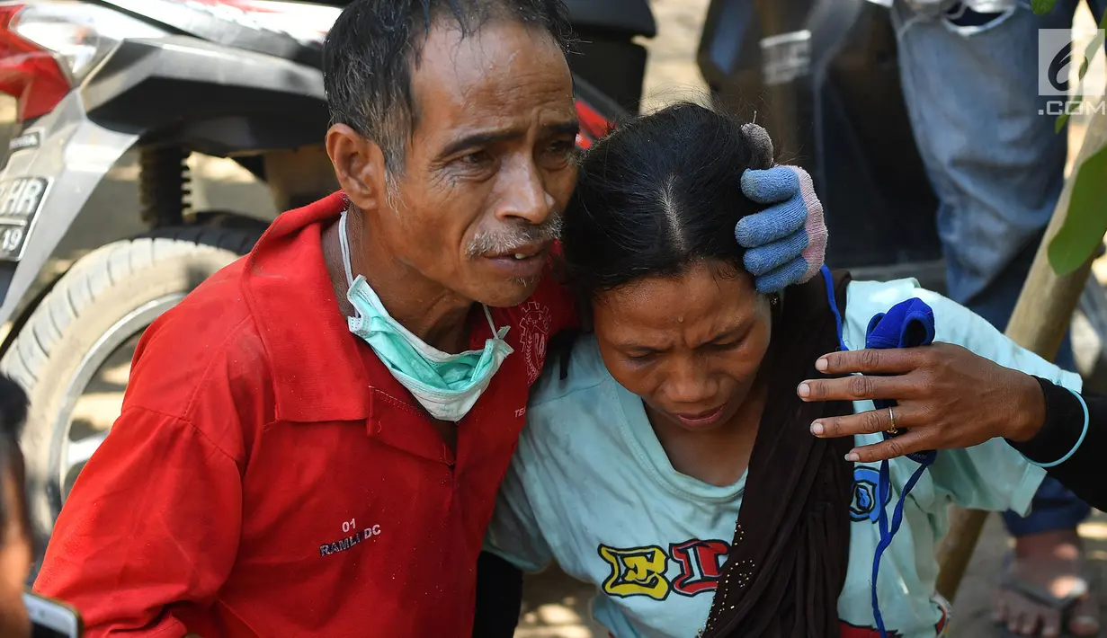 Seorang pria mencoba untuk menenangkan salah satu keluarganya saat  gempa susulan terjadi di Tanjung pulau Lombok, NTB, Kamis (9/8).(AFP/ ADEK BERRY)